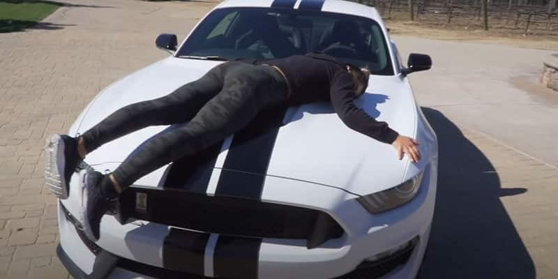 Hailie laying on top of her Mustang