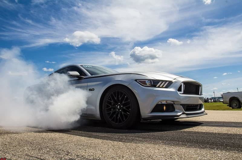 Silver 2015 Mustang GT with smoke coming off wheels