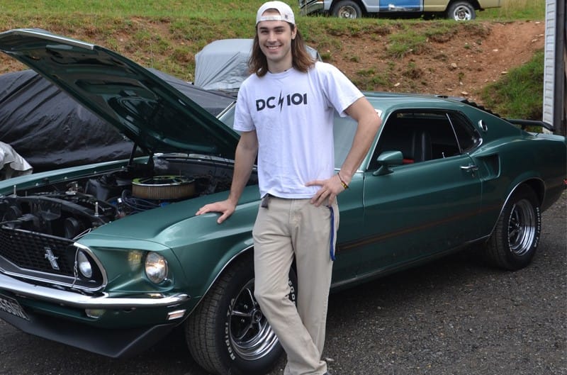Brian posing next to green Mach 1 with hood open in parking lot