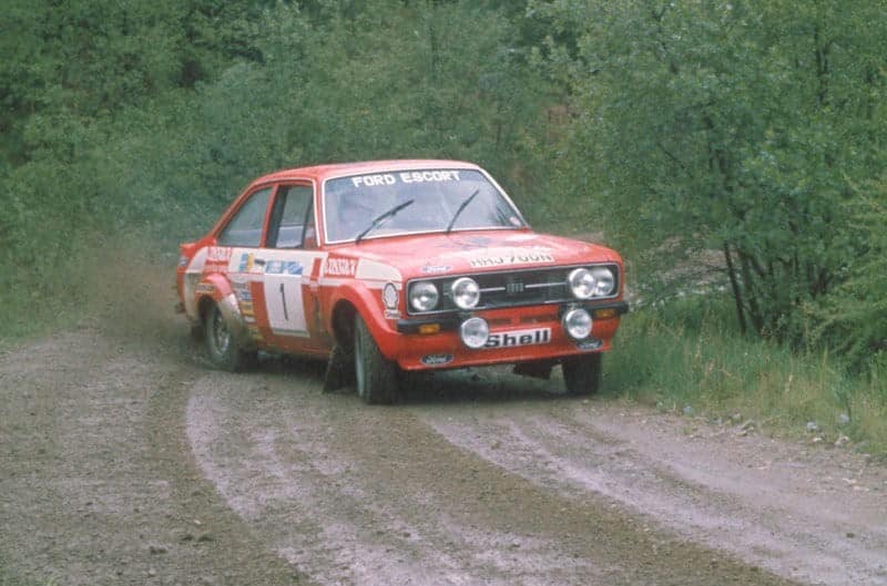 Front of a red Ford Escort drifting on a dirt road