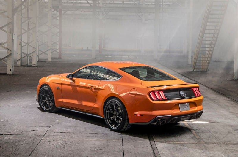 A rear side view of an orange Mustang 