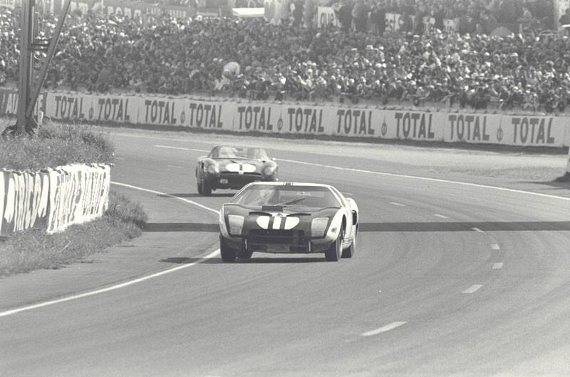 Two classic vehicles making a right turn in a race in 1964 