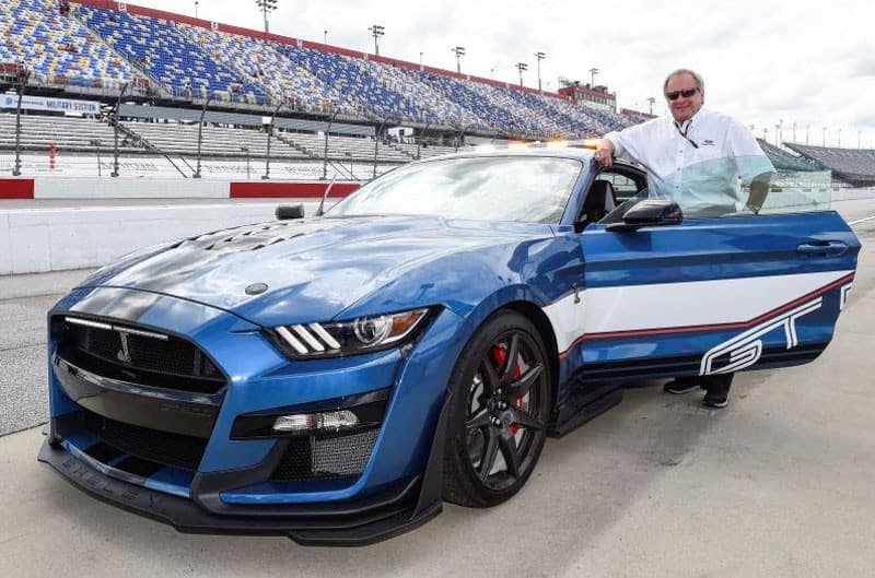 Edsel B. Ford II standing next to blue Mustang GT on the track