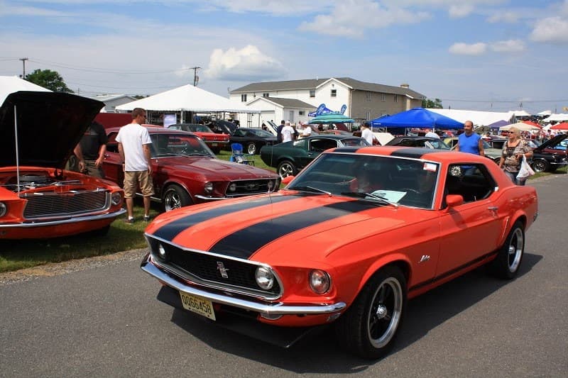 Red Mustang with black stripes at car show