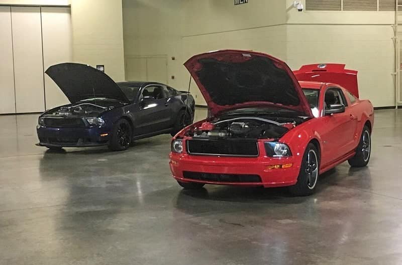 Red and black Mustang Bullitts with hoods up in garage 
