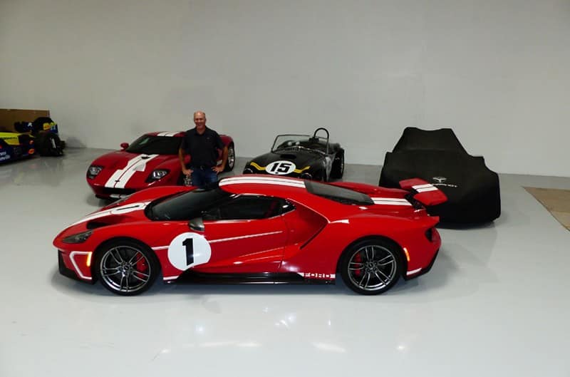 Justin Gurney in front of various Ford GTs in a garage 