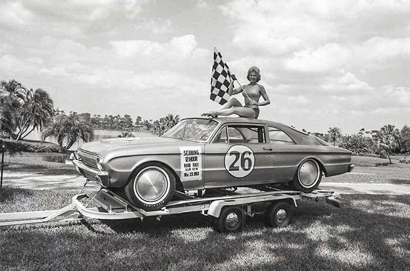Ford Falcon race car on trailer with women sitting on top