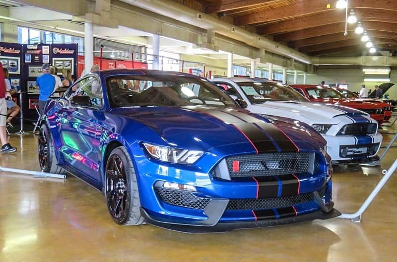 A blue Ford Mustang with a black stripe down the center on display