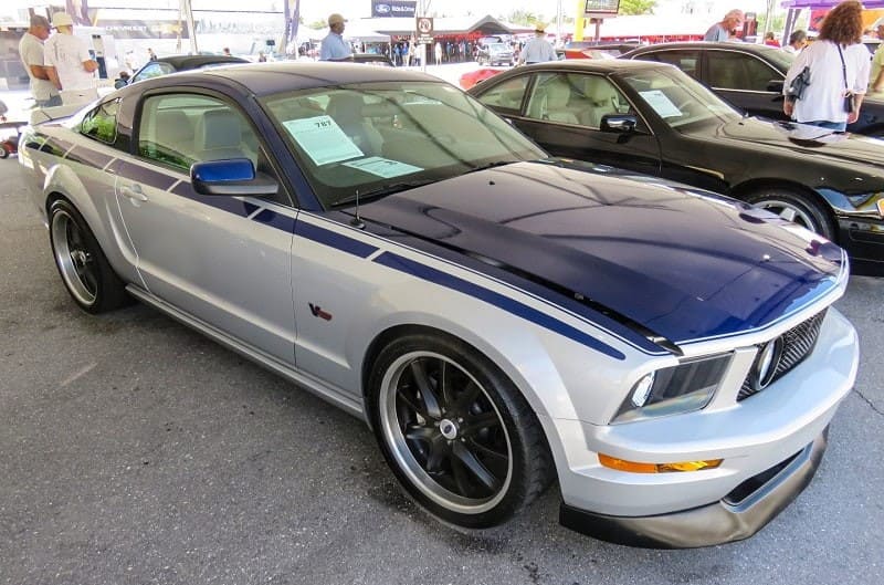 A front side view of a blue and silver Ford Mustang