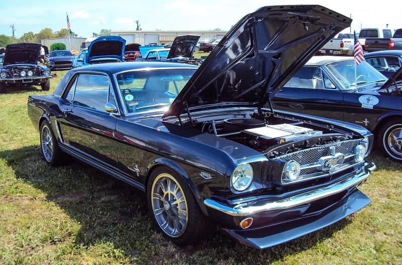 A classic two door Ford Mustang on display with the hood up