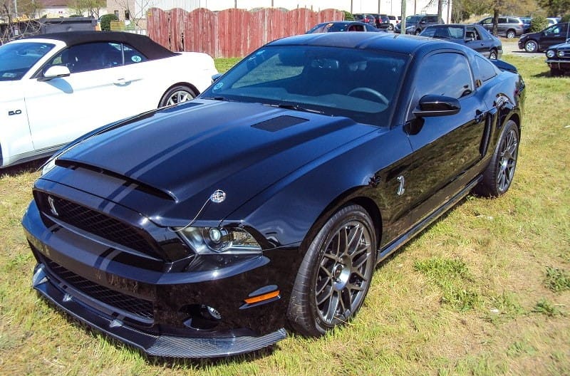 A front side view of a black Mustang on display 