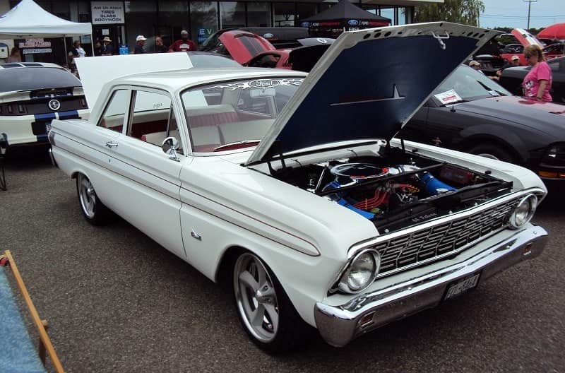 A classic white vehicle on display with the hood and trunk open 
