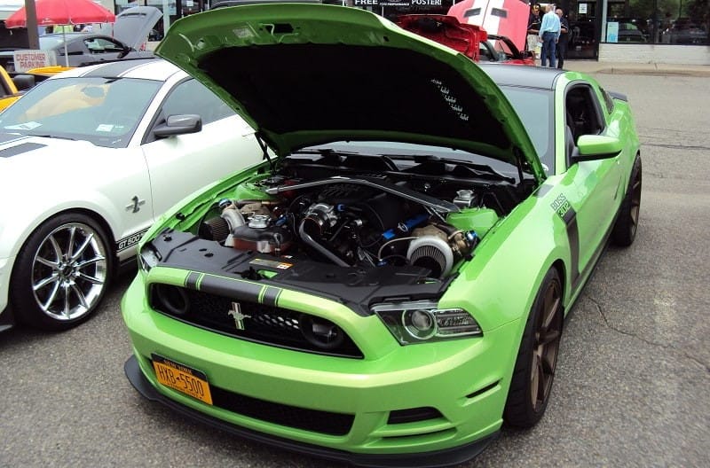 A front end view of a light green Ford Mustang with the hood up 