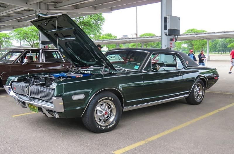 A classic green Ford Mustang on display with the hood up 