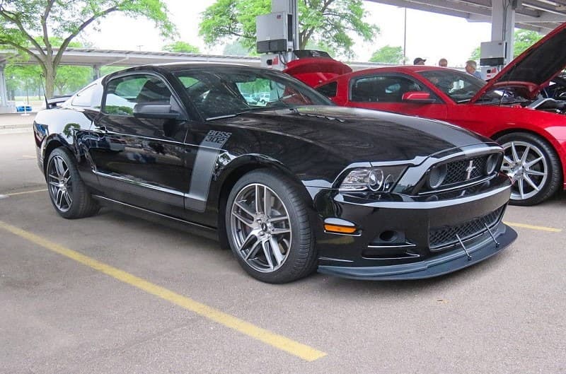 A black Ford Mustang on display next to other Mustangs 