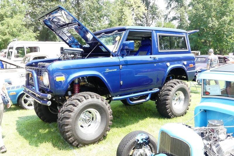 A side view of a blue Ford Bronco with the hood up 