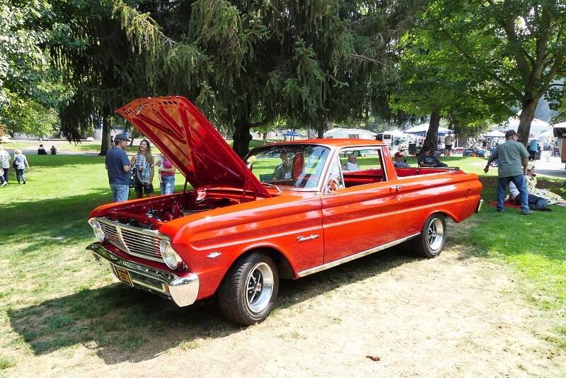 A classic red vehicle on display with the hood up 