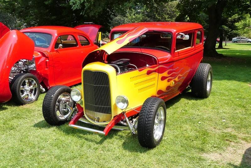 A red hot rod with yellow flames on display with the hood up 
