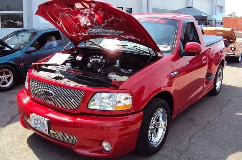 A red Ford truck on display with the hood up 