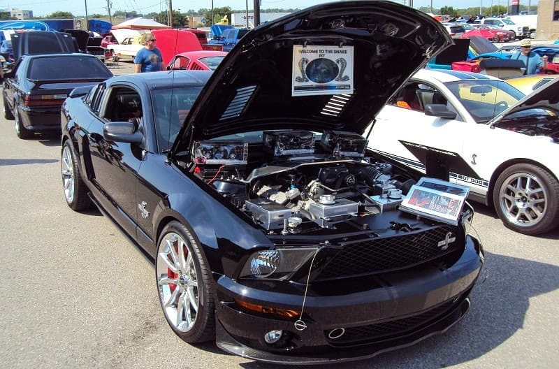 A black Mustang on display with the hood up 