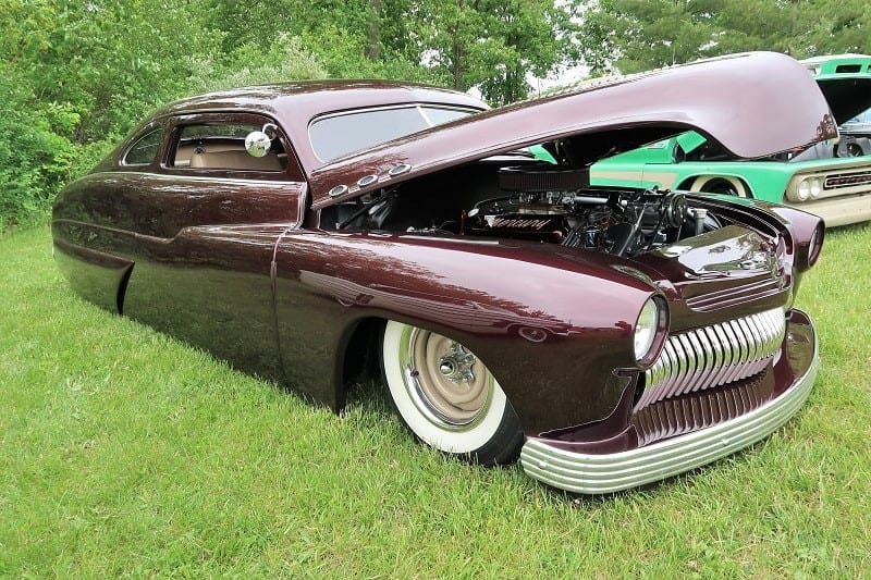 A front side view of a classic maroon vehicle on display 