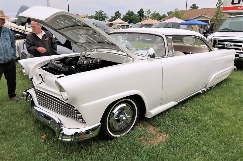 A front side view of a classic white vehicle on display at the car show 