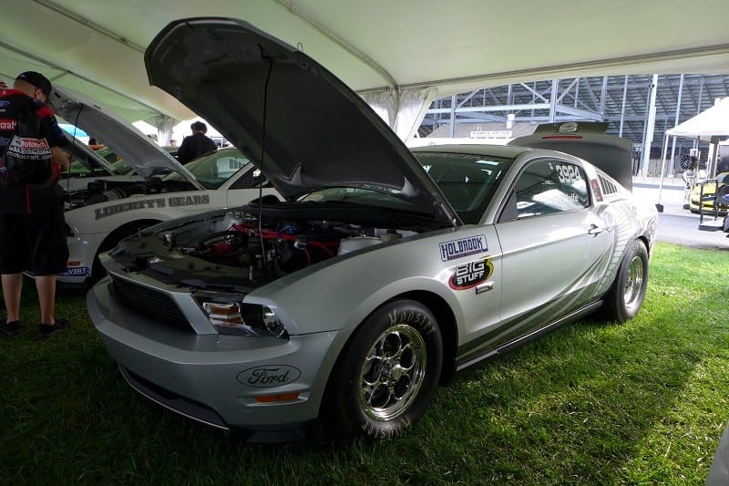 A front side view of a silver Mustang Cobra Jet on display with the hood up 