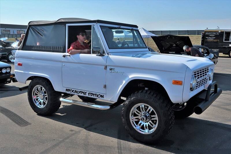 Two people inside a white Ford Bronco 