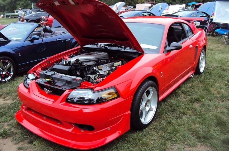 A red Ford Mustang on display with the hood up 
