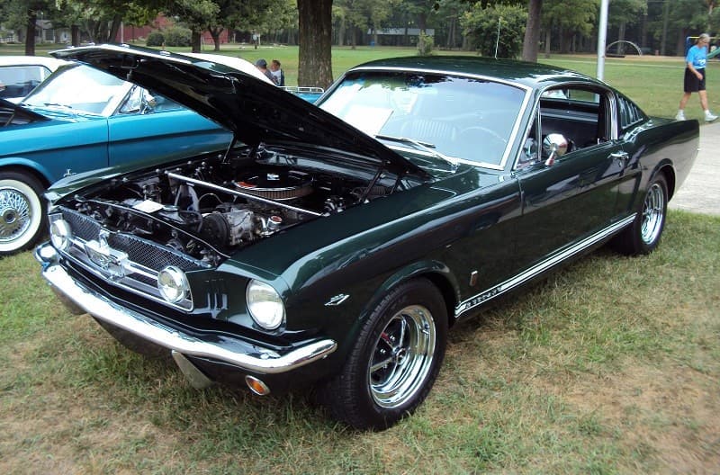 A classic green Mustang on display with the hood up 