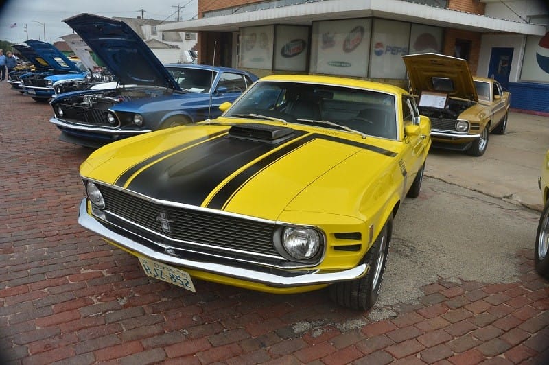 A front end view of a classic yellow Ford Mustang on display 