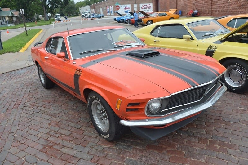 A front side view of a classic dark orange and black Ford Mustang 