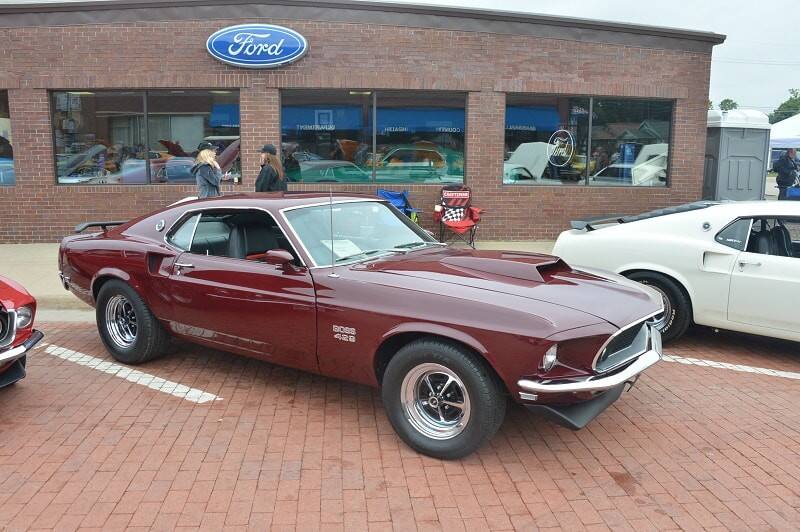 A front side view of a classic maroon Mustang on display 