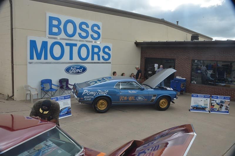 A classic blue Ford Mustang on display in front of a Boss Motors sign 
