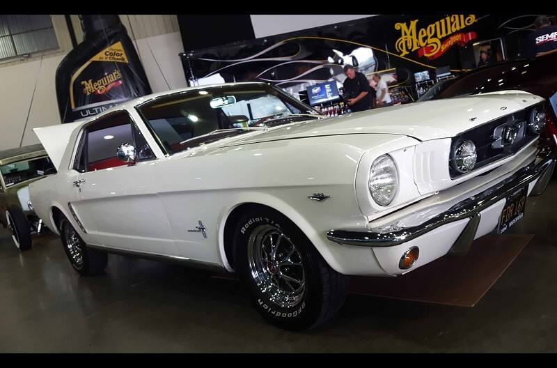 A front side view of a classic white Ford Mustang on display