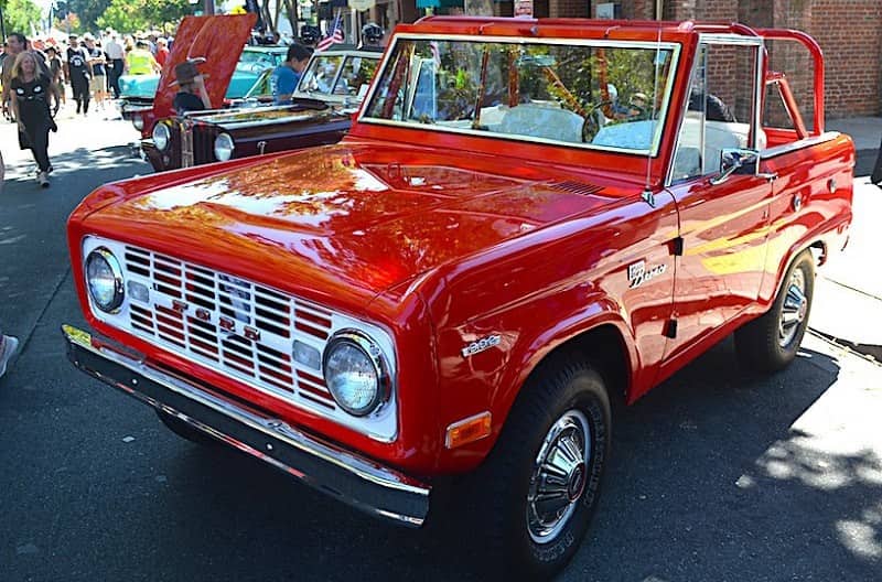 A front side view of a classic red Ford Bronco 