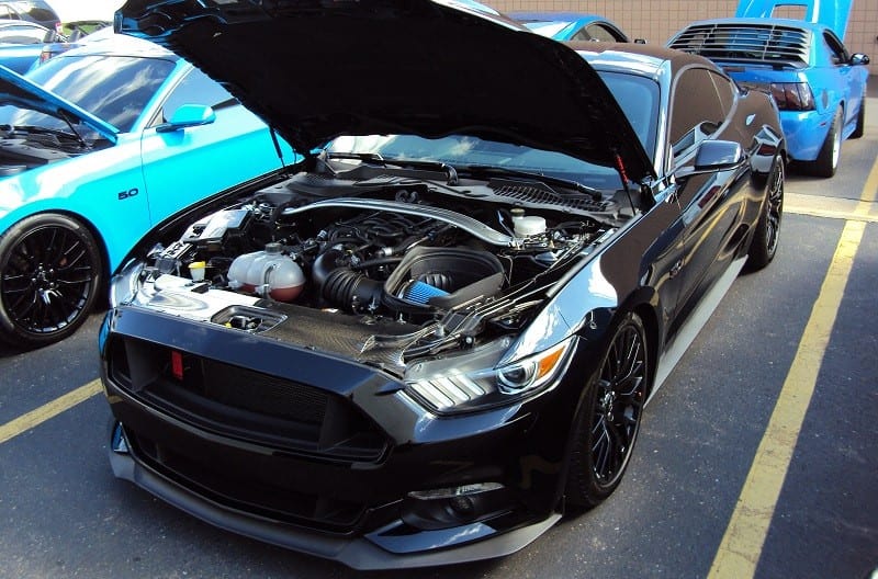 A black Ford Mustang on display with the hood up 