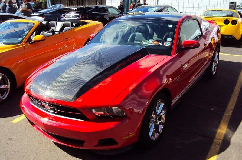 A front side view of a black and red Mustang on display