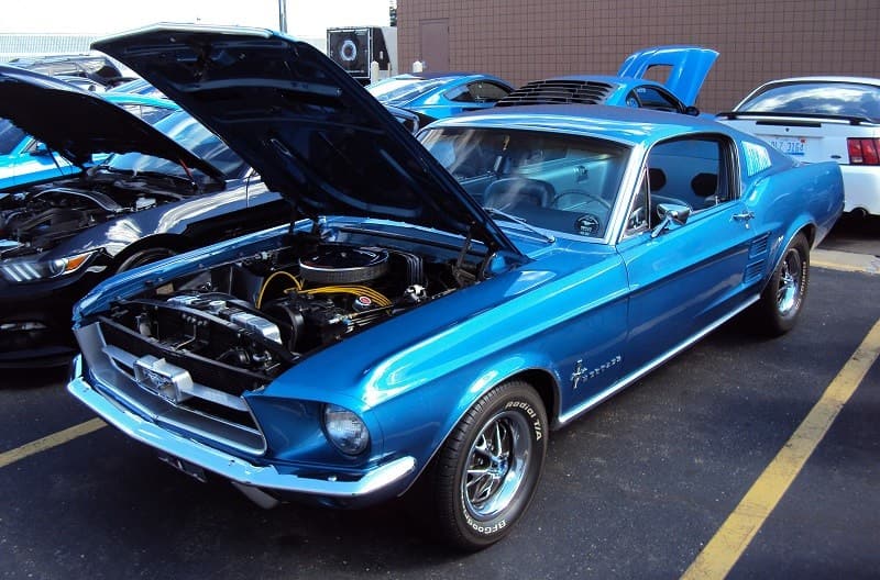 A classic blue Mustang on display with the hood up 
