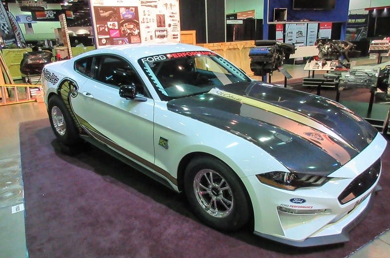 A front side view of a white Mustang on display 