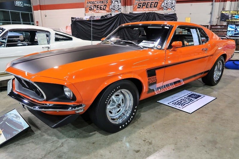 A front side view of an orange and black Mustang Boss 302 on display 