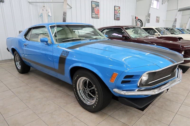 Front profile of blue Mustang Boss 302 with black stripe on hood parked in building 