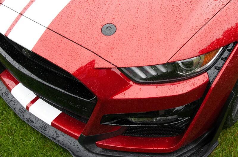 A closeup of the front hood of a red Mustang 