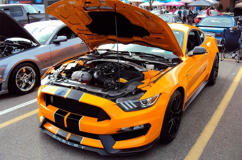 A front side view of an orange and black Mustang 