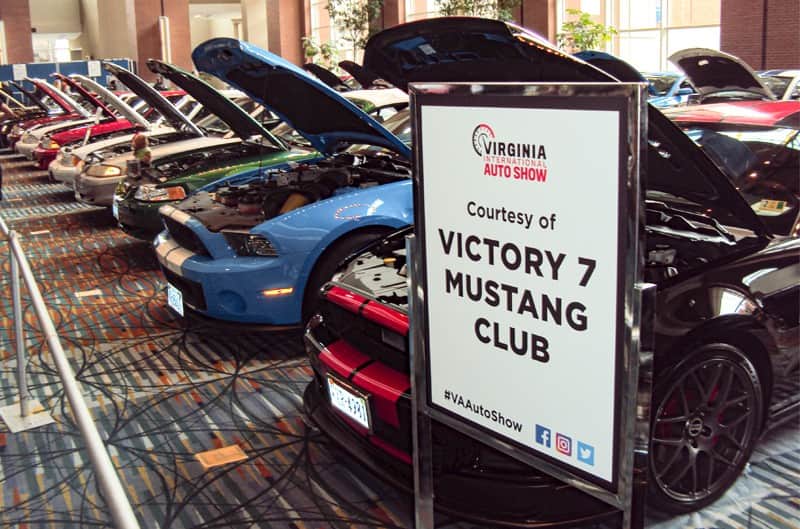 Victory 7 Mustang Club sign in front of various Mustangs lined up on display