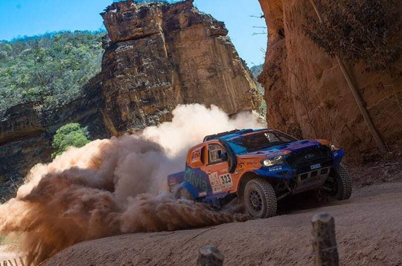 The Neil Woolridge Motorsport Ford Ranger kicking up dust while keeping close to the rock wall beside them 
