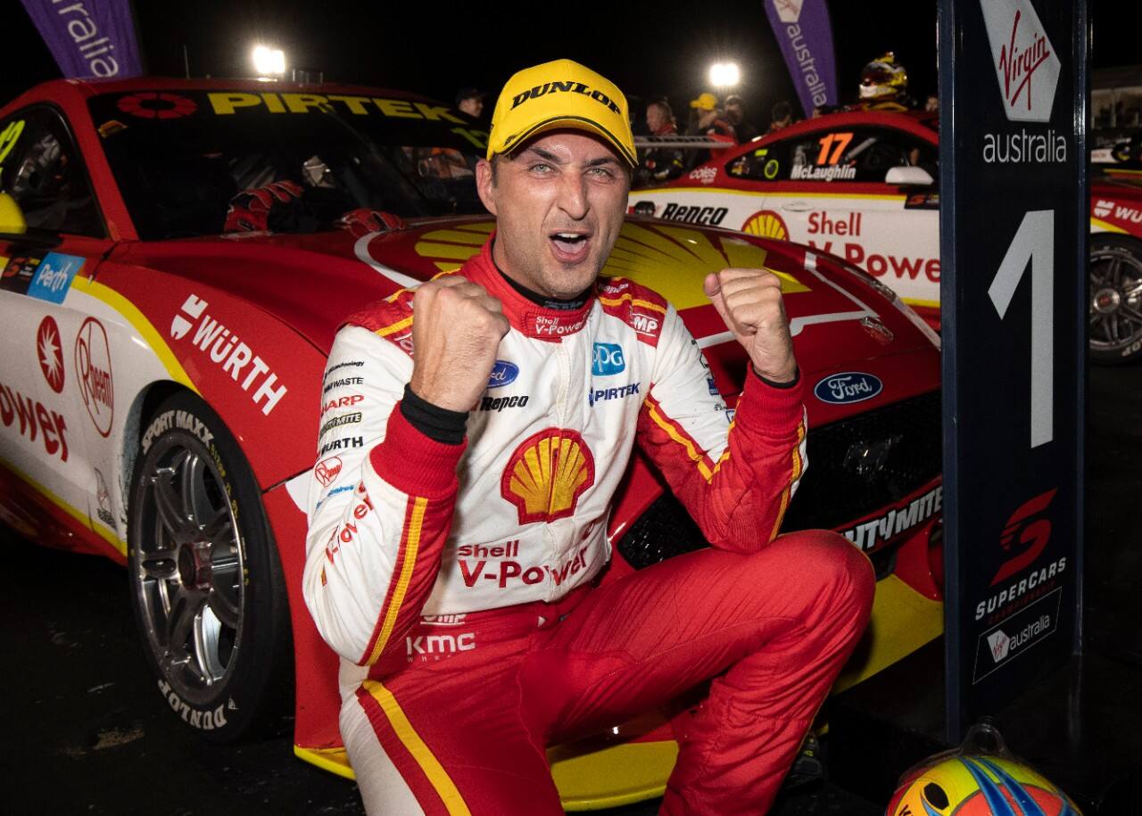 Fabian Coulthard squatting in front of his car while holding up two fists celebrating his win