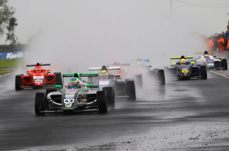 Seven Formula Ford vehicles battling the wet surface of the track