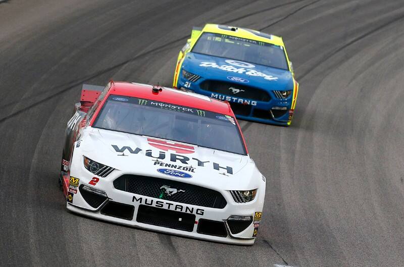 Brad Keselowski ahead of the number 21 Ford Mustang while zooming around a corner