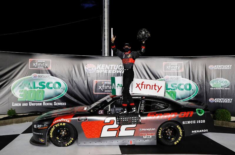 Austin Cindric standing on top of his Mustang celebrating his win on victory lane 